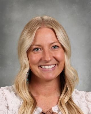 The woman is wearing a black turtleneck and smiling for the camera.