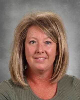 A woman in a green shirt is smiling for the camera.