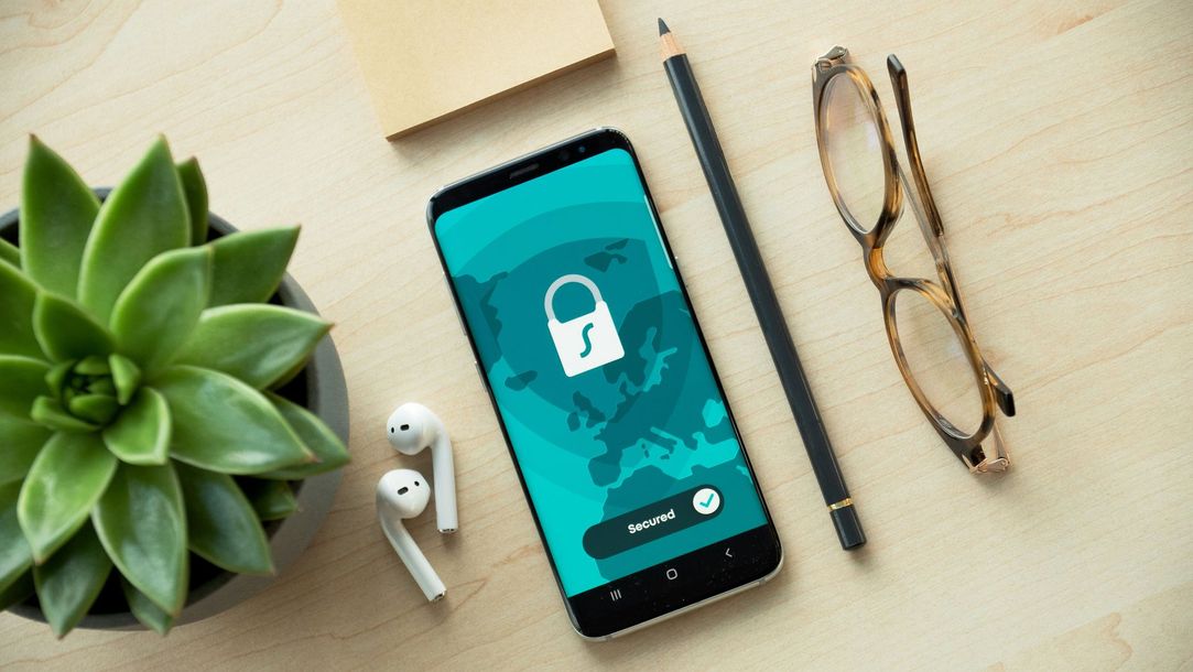 A cell phone with a padlock on the screen is sitting on a wooden table.