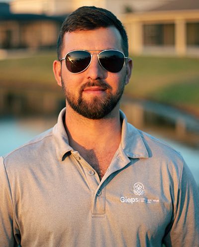 A man with a beard wearing sunglasses and a polo shirt.