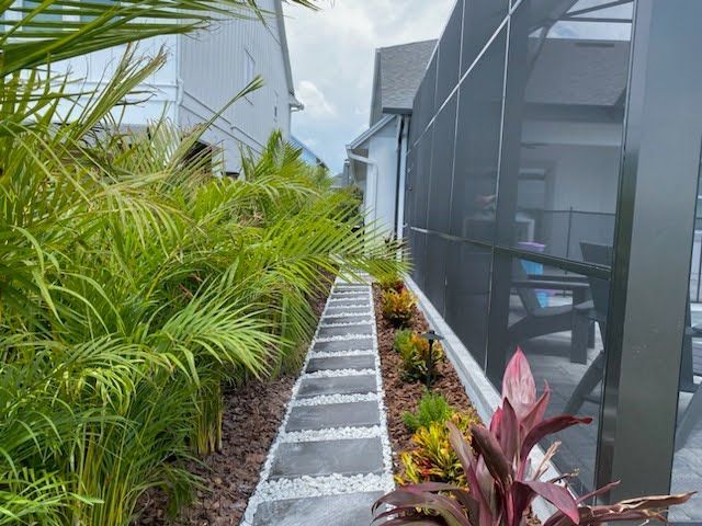 A walkway leading to a screened in porch next to a house.