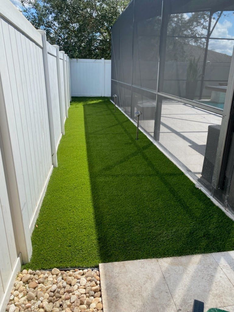 A long grassy yard with a white fence and a screened in porch.