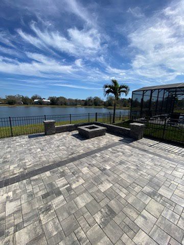 A patio with a fire pit and a lake in the background.