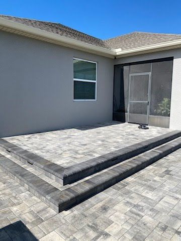 There is a patio in front of a house with a screen door.