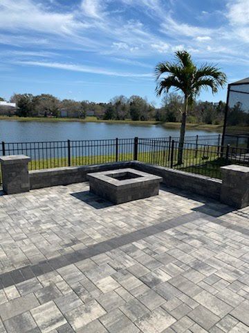 A patio with a fire pit and a lake in the background.