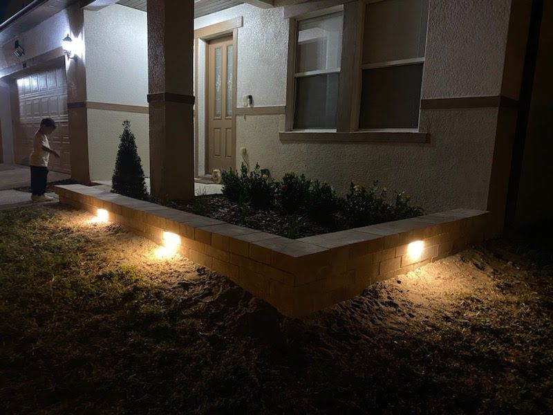 A person is standing in front of a house at night with lights on.