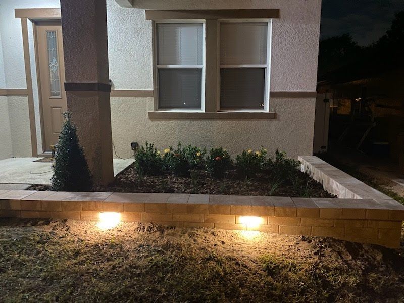 A house with a window and a planter in front of it at night.