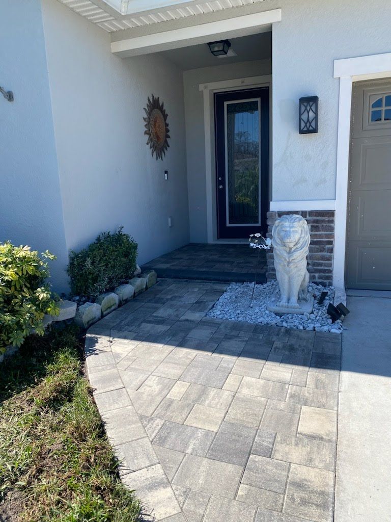 A statue of a lion is on the sidewalk in front of a house.