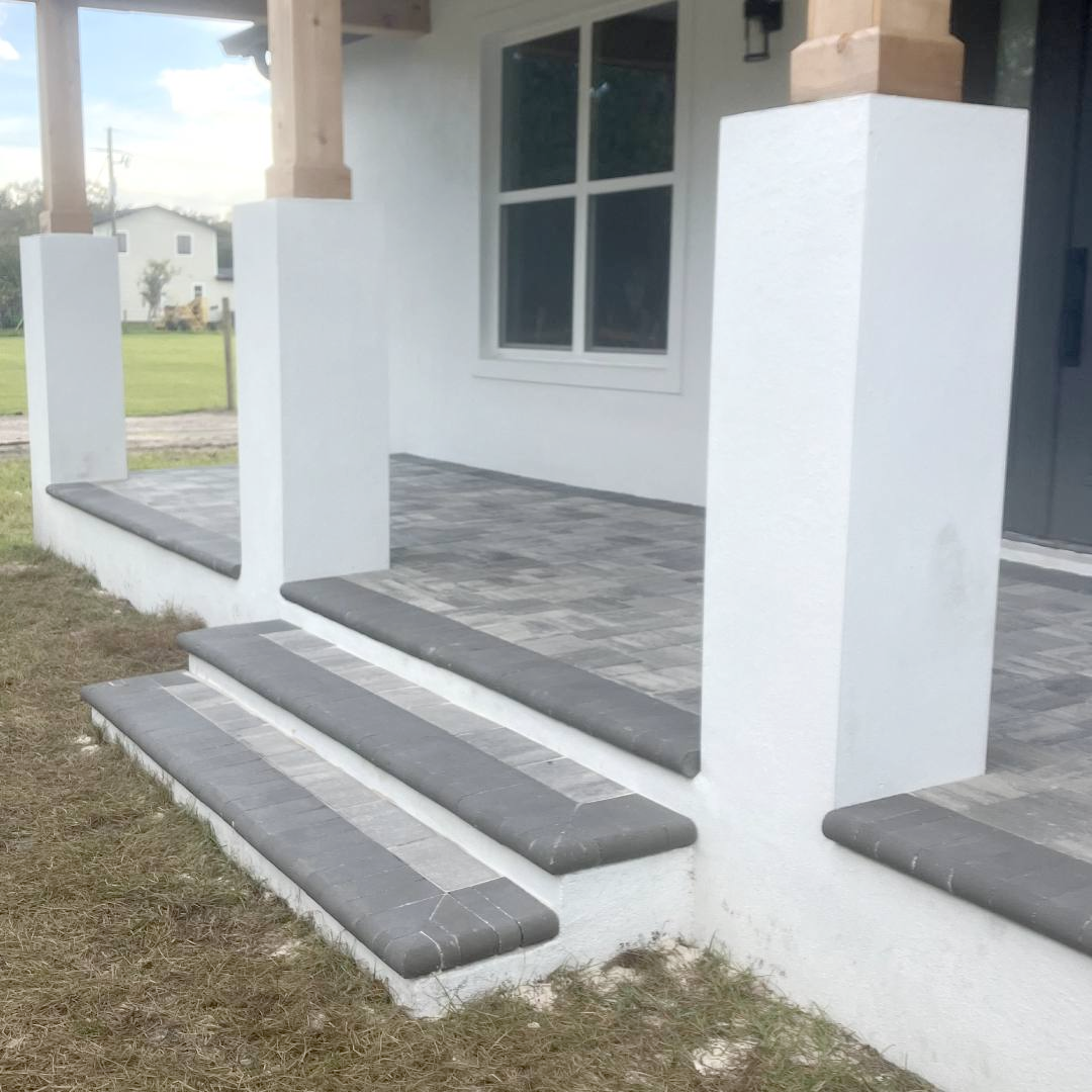 A white house with a porch and steps leading up to it.