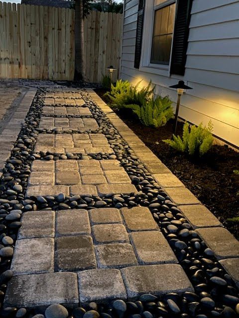 A stone walkway leading to a house at night