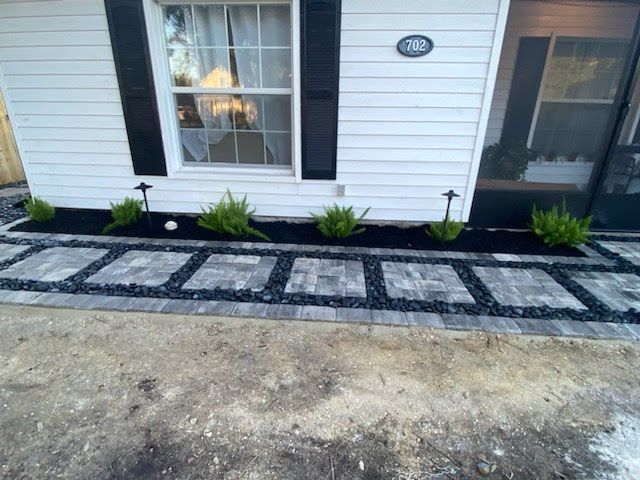 A white house with black shutters and a walkway in front of it.