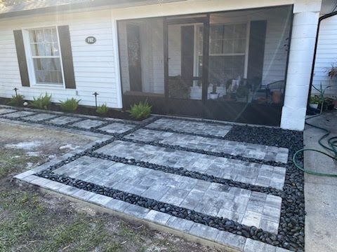 A patio with a screened in porch and a hose in front of a house.