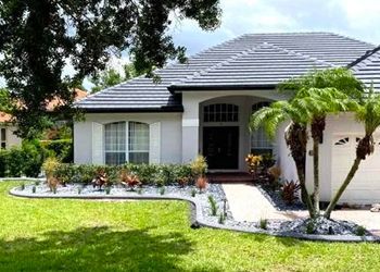 A white house with a tile roof and palm trees in front of it