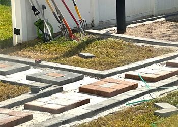 A row of gardening tools sitting on top of a brick walkway.