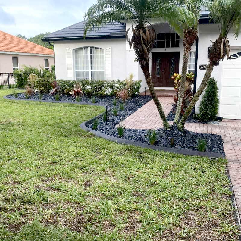 A white house with a lush green lawn and palm trees in front of it.
