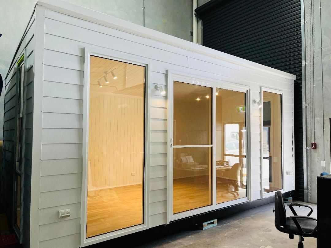White prefabricated building with large glass doors and windows; indoors, bright.