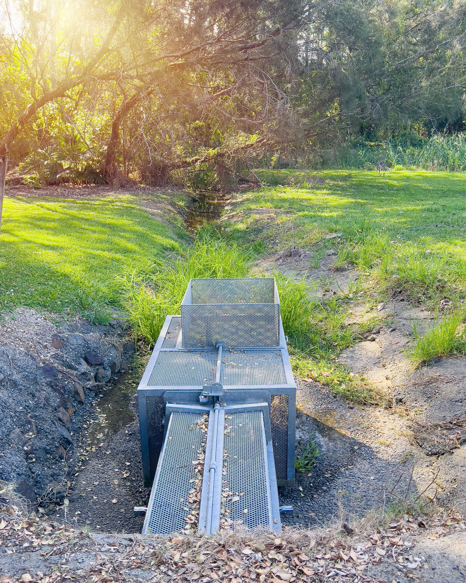 A metal bridge is sitting in the middle of a grassy field.