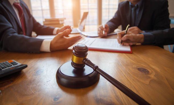 A judge 's gavel is sitting on a wooden table next to two men in suits.