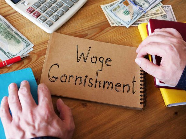 A person is writing in a notebook that says wage garnishment