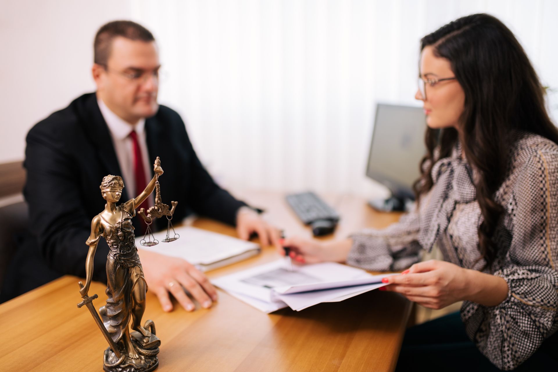 A man and a woman are sitting at a table with a statue of justice.