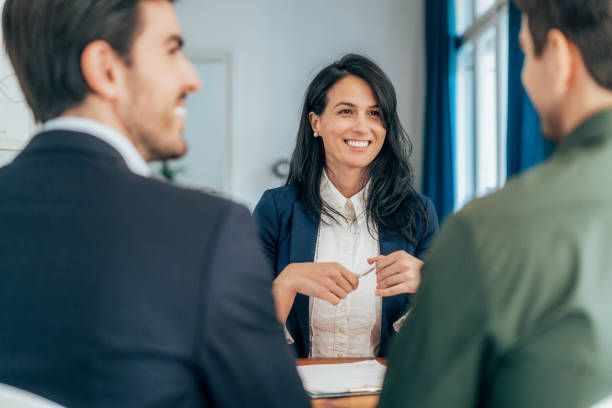 A woman is sitting at a table talking to two men.