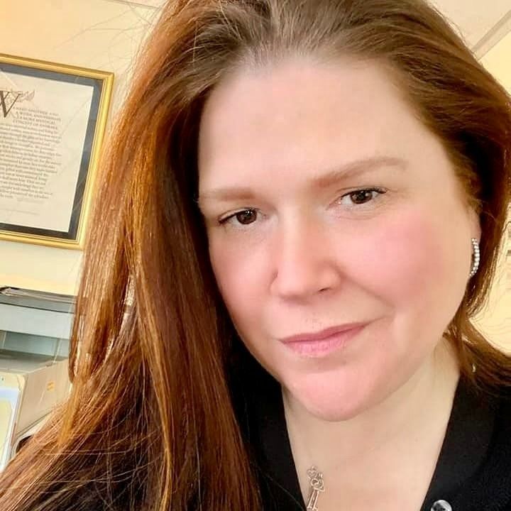 A woman with long red hair is smiling for the camera