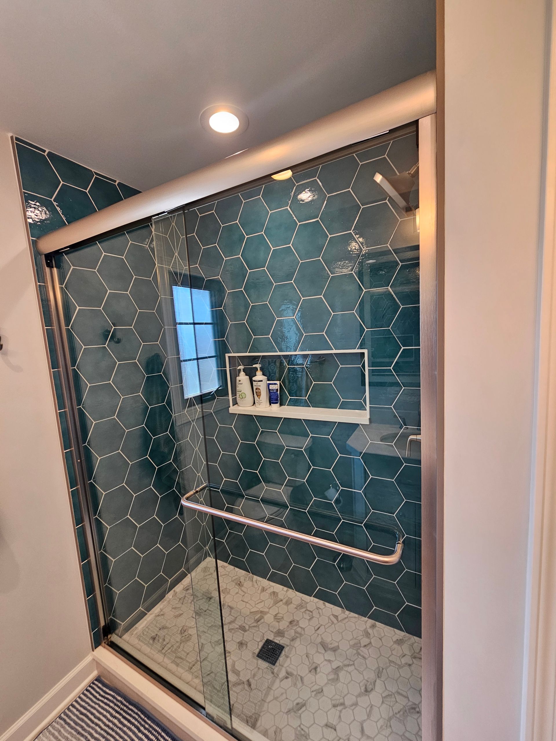A bathroom with green tiles and a sliding glass shower door.