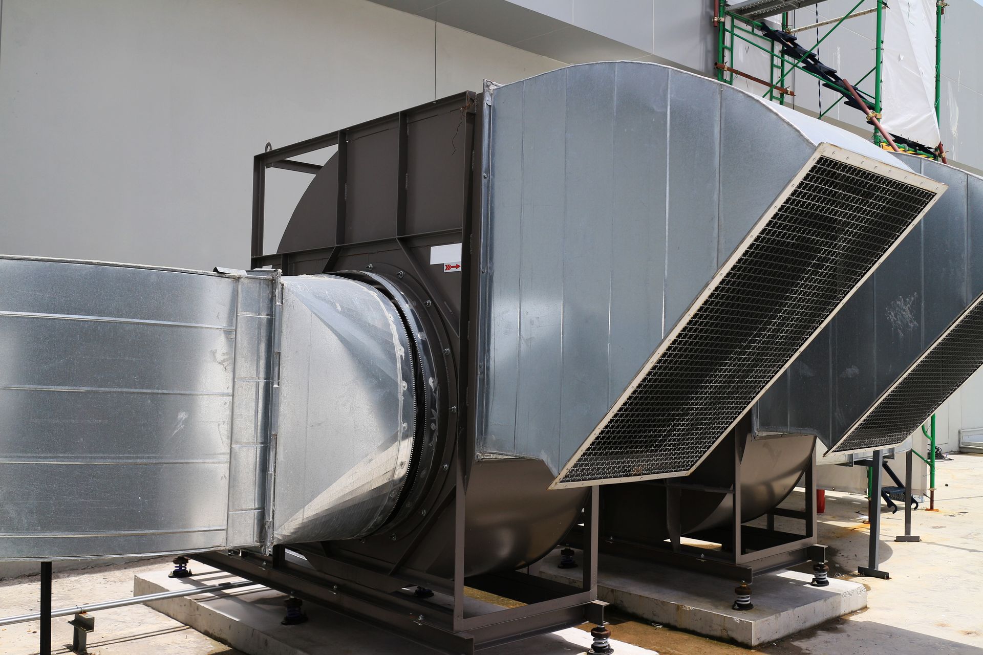 Large, silver HVAC system on a rooftop, with ductwork and cooling coils.