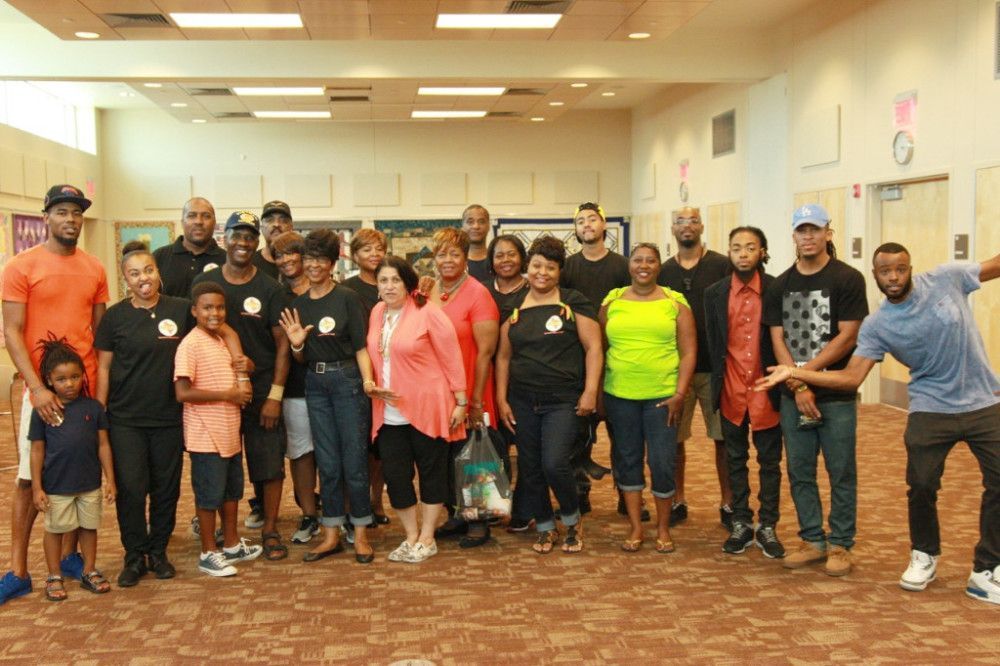 Group of people posing indoors; some wearing black shirts, others smiling.