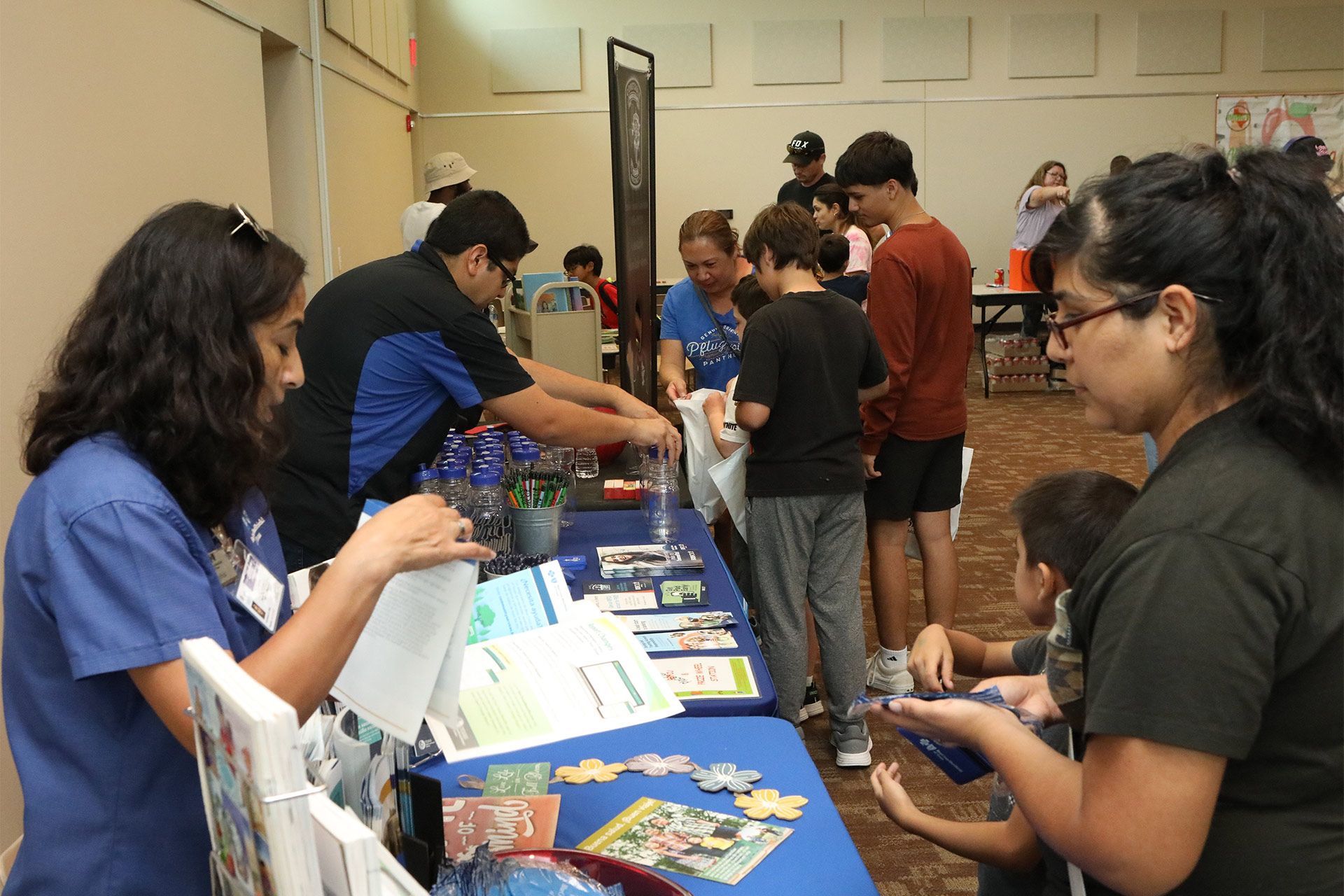 People at a table with books and puzzles, interacting at an event.