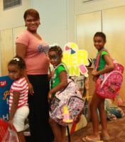 Woman and three girls with backpacks pose near a 