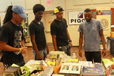 Four men looking at items on a table in a room.