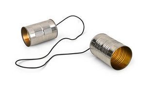 Two tin can telephones connected by a black string, lying on a white surface.