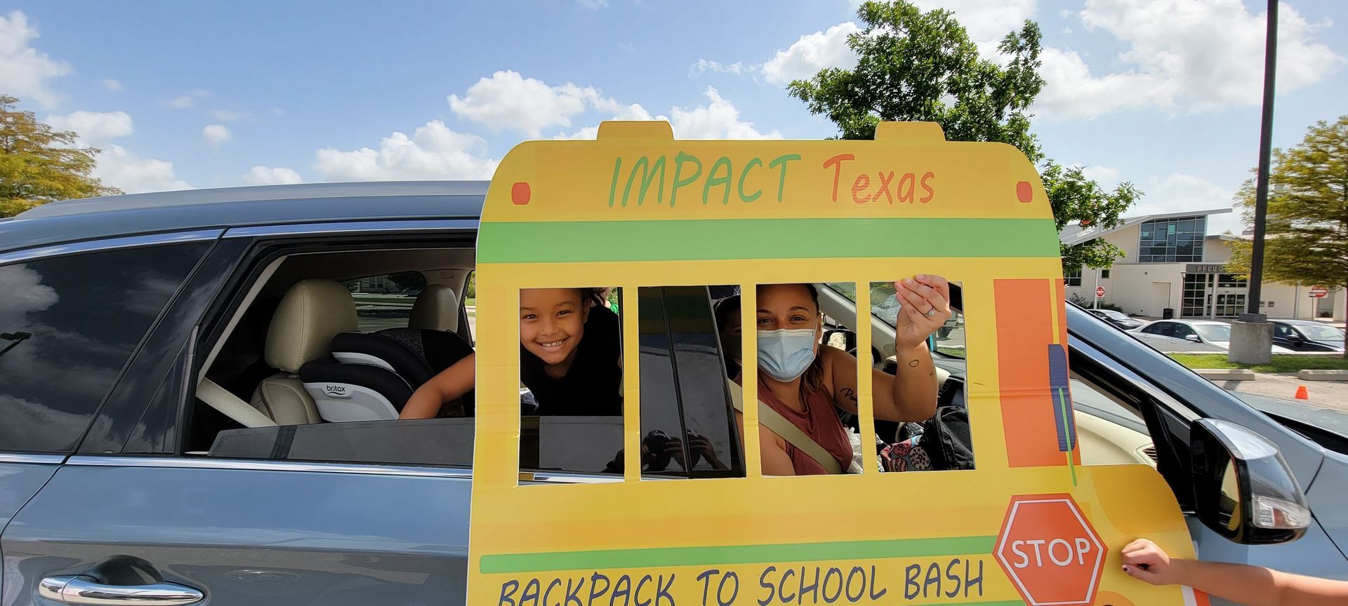 People in a car decorated as a school bus. Impact Texas Backpack to School Bash sign.
