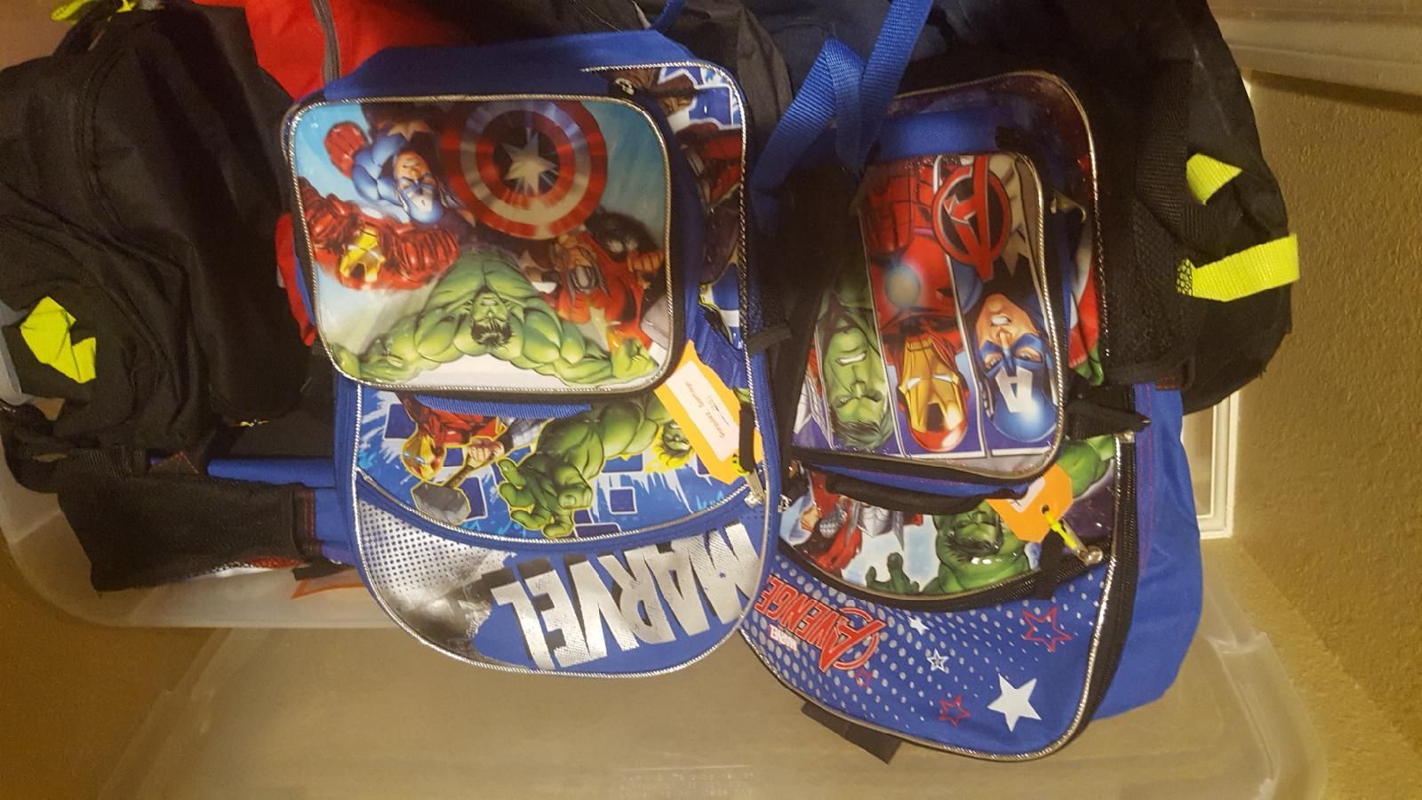 Two blue Marvel-themed lunch bags with matching lunch boxes, sitting inside a container.