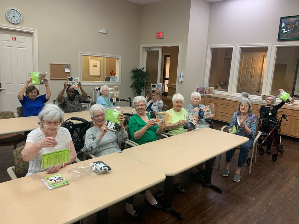 A group of people sitting at tables, holding green objects, indoors.