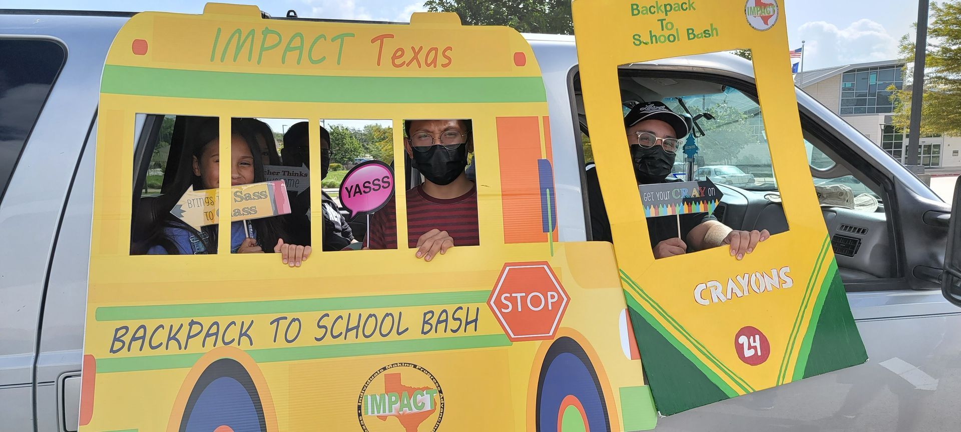 People in a car with cardboard cutout of a school bus and a crayon, for a 