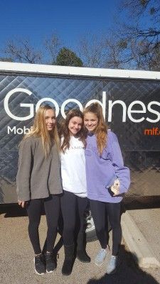 Three people stand in front of a food truck with