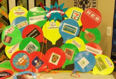 Colorful cut-out balloons with company logos displayed on a table.
