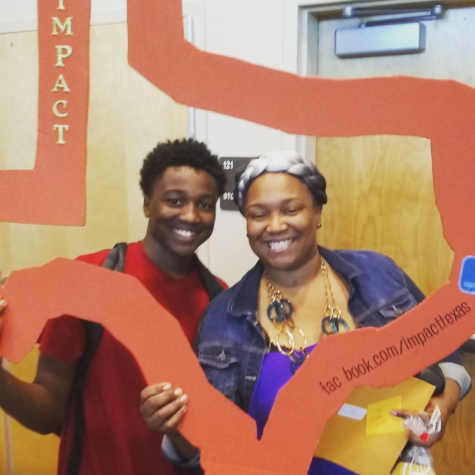 Two smiling people hold a large orange cutout of the word 