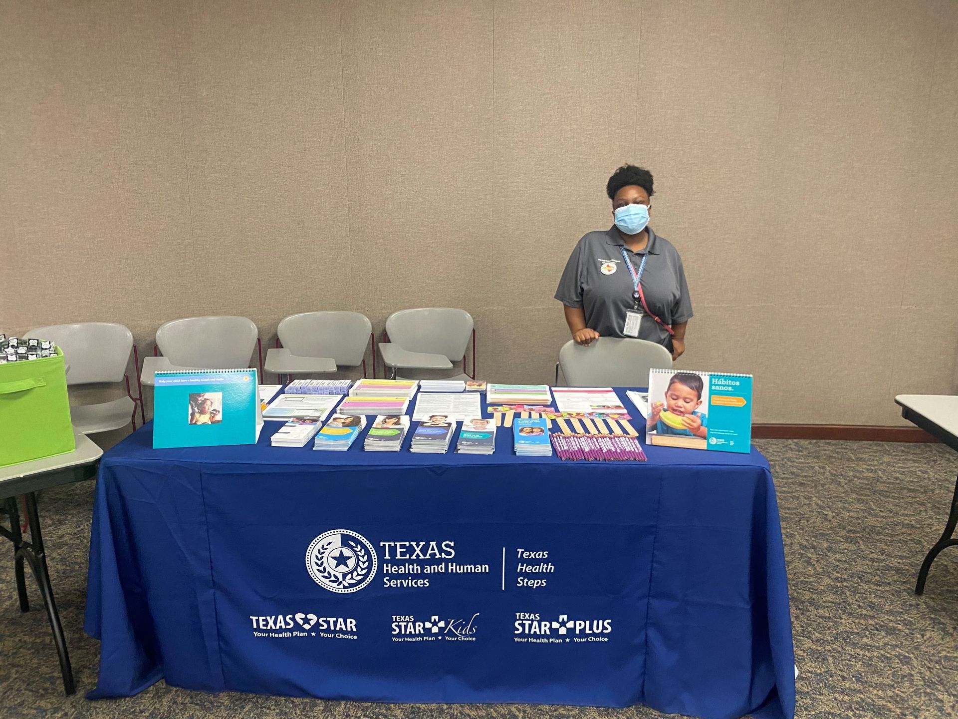 A person stands behind a table with informational brochures. The table has a blue Texas Health and Human Services logo.