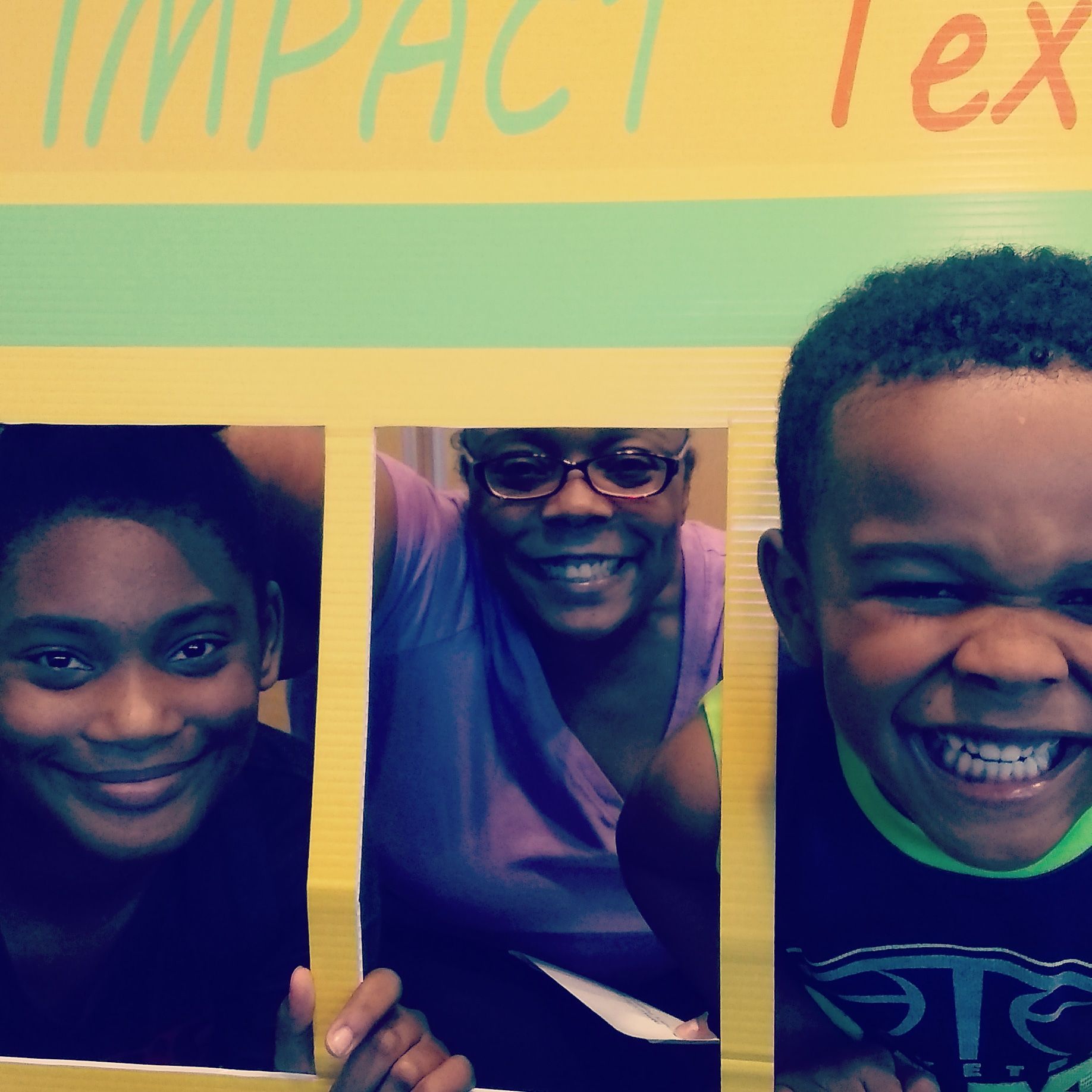 Three smiling people, framed in a yellow cutout; a woman and two children with the word 