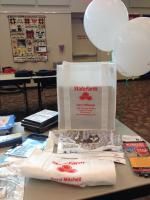 Table with State Farm branded bags, balloons, and promotional materials.