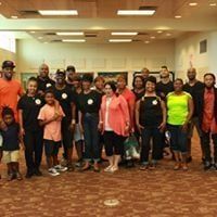 Group of people in a large room, some holding books.