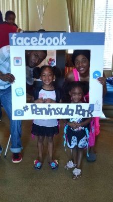 Group of people posing with a Facebook photo booth frame at Peninsula Park.
