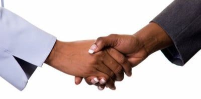 Two hands, one in a light blue sleeve, and one in a dark gray sleeve, shake hands on a white background.