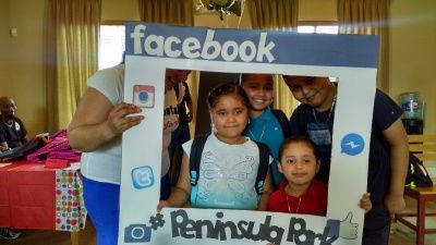 Children posing behind a Facebook photo frame at Peninsula Park.