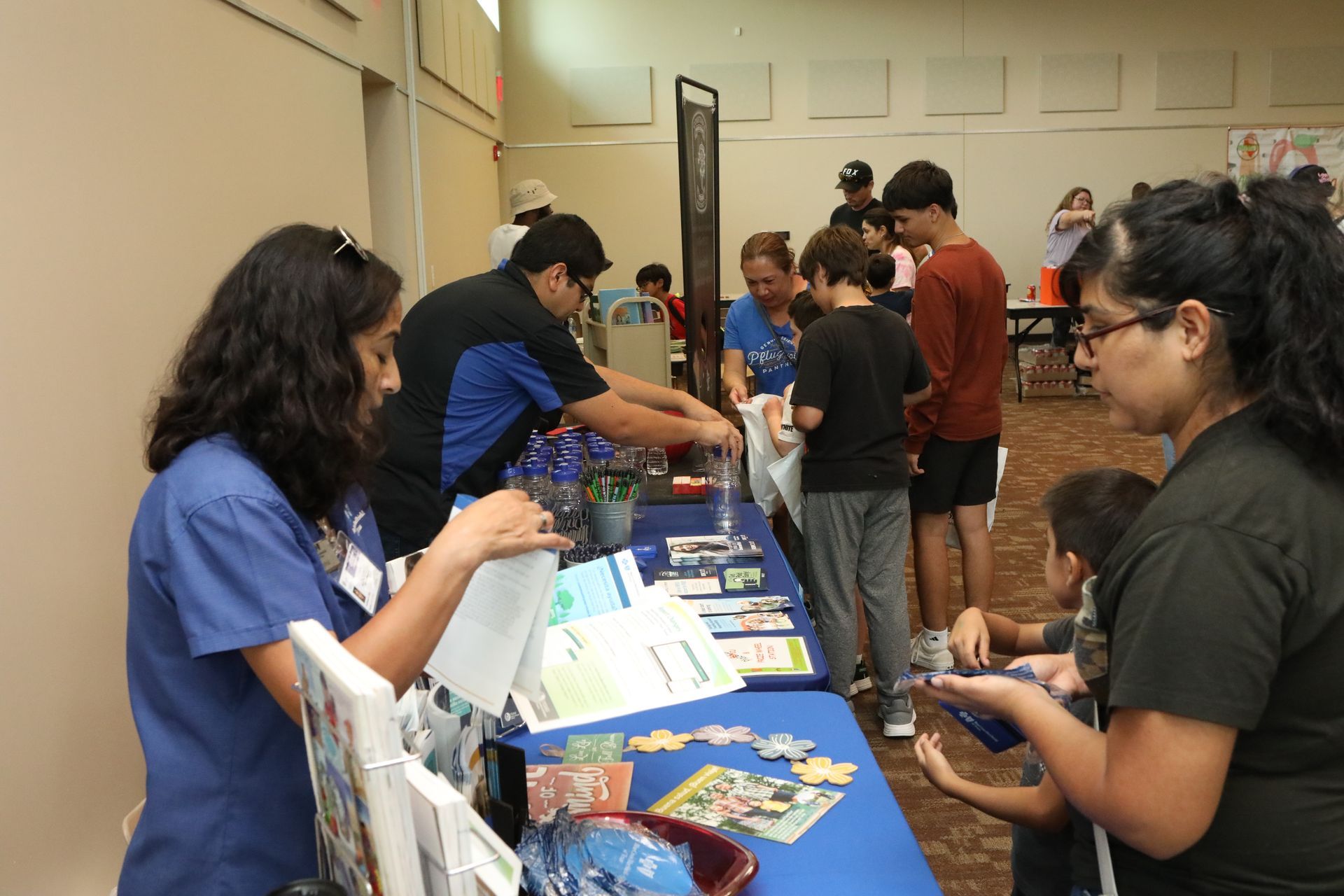 People at a table with materials, possibly an information booth or event.
