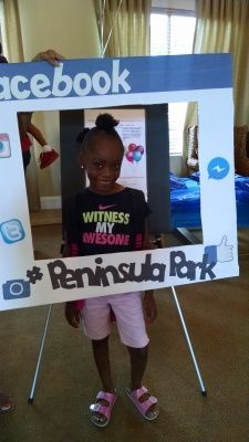 Girl posing with a Facebook frame at Peninsula Park. She wears a black shirt, pink shorts, and sandals.