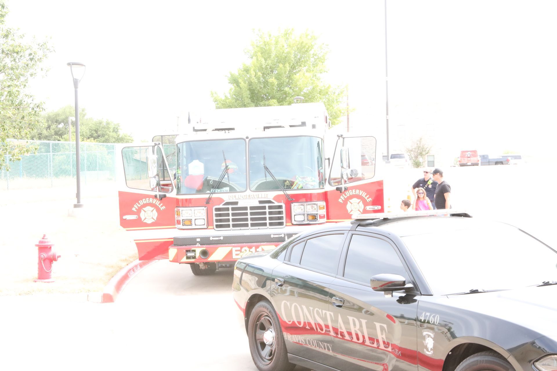 Fire truck and constable car parked outside; people in the background.